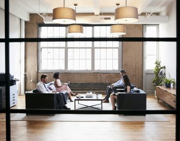 business people in lounge meeting area seen through window