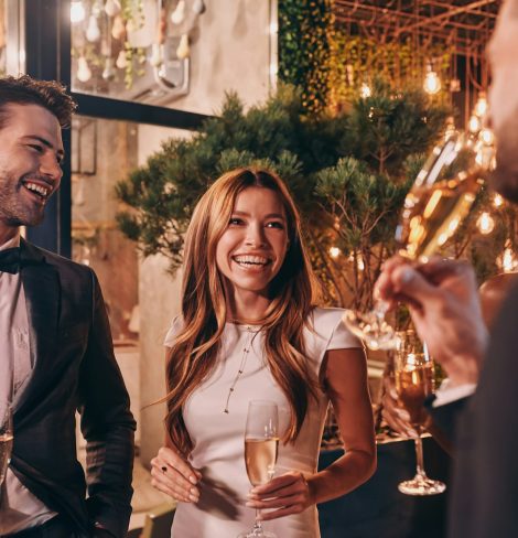 group of people in formalwear communicating and smiling while spending time on luxury party